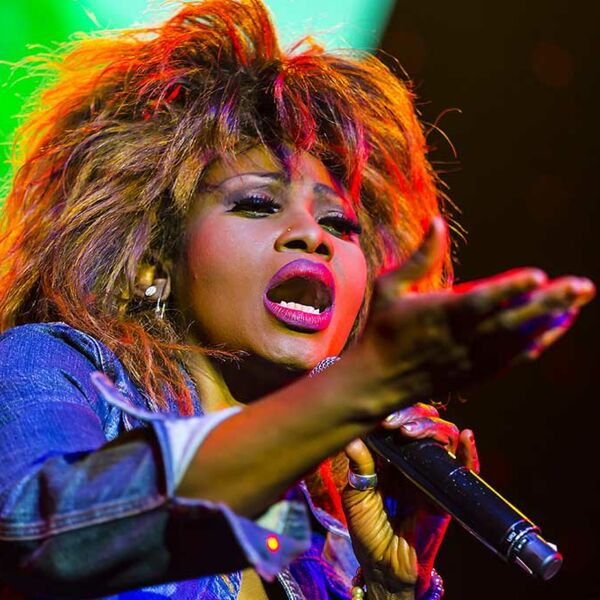 Nahaufnahme von Coco Fletcher alias Tina Turner mit Mikro und mit Jeansjacke