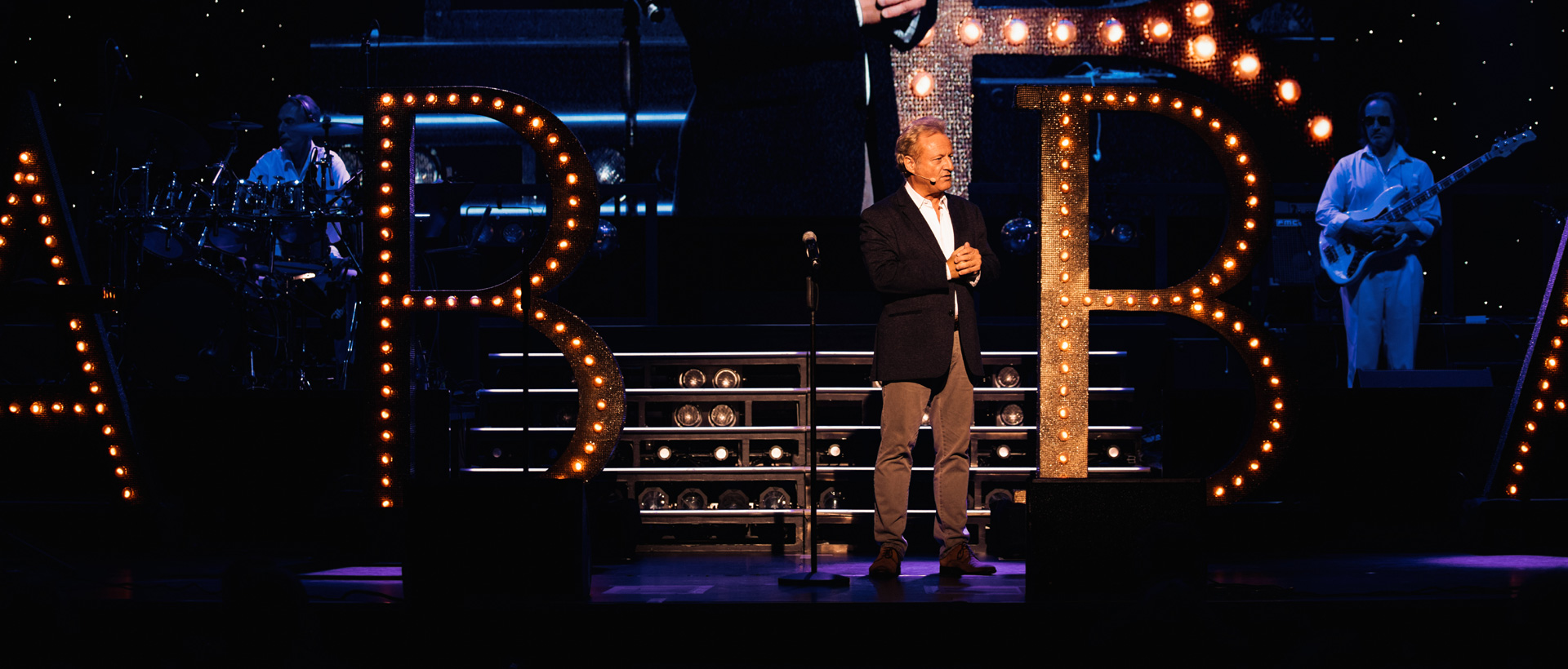 Moderation Uwe Huebner_ABBA_2024_live Berlin on stage with LED letters