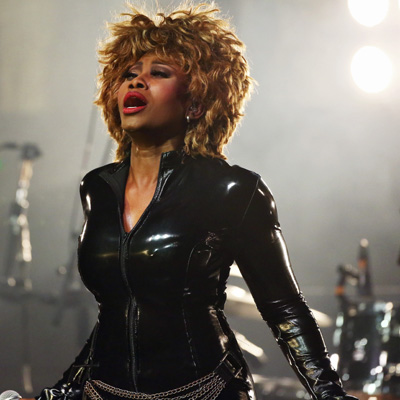 Coco Fletcher als Tina Turner singend auf der Bühne im schwarzem Lack Kostüm